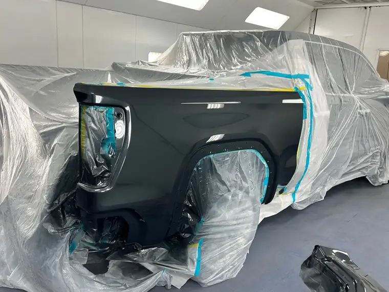 The same pickup bed painted black under masking film in the booth