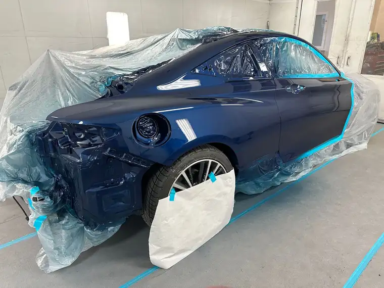 The same coupe's rear painted blue under masking in the booth