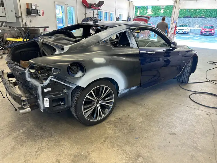 A dark blue coupe stripped at the rear with bare and primered panels