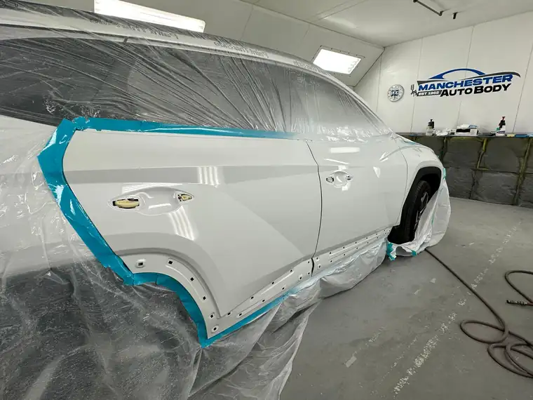 The same white car masked in the booth after the doors were refinished