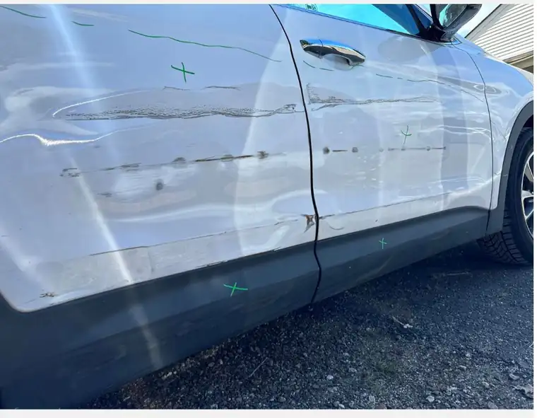Long scratches marked along the doors of a white car
