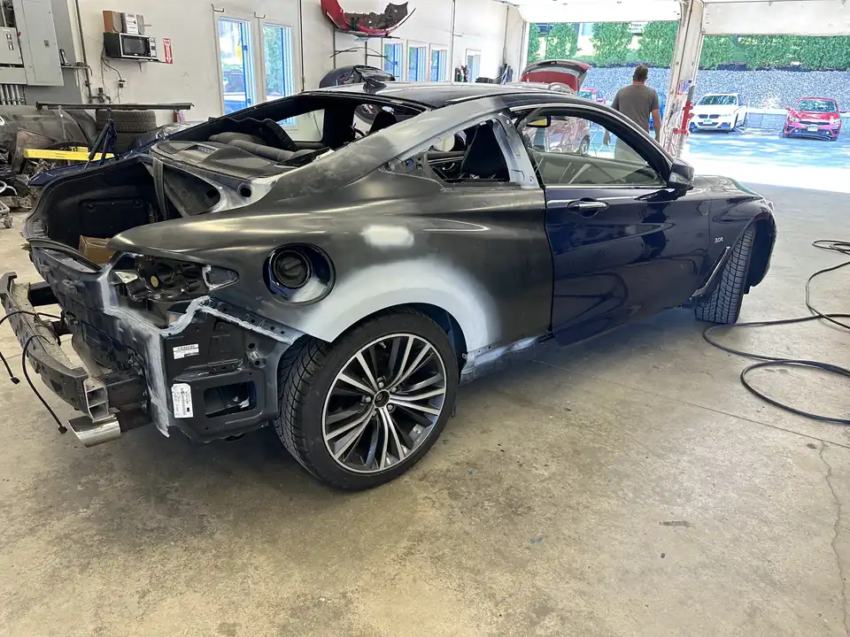 An Infiniti coupe in the body shop with its rear quarter panel in primer